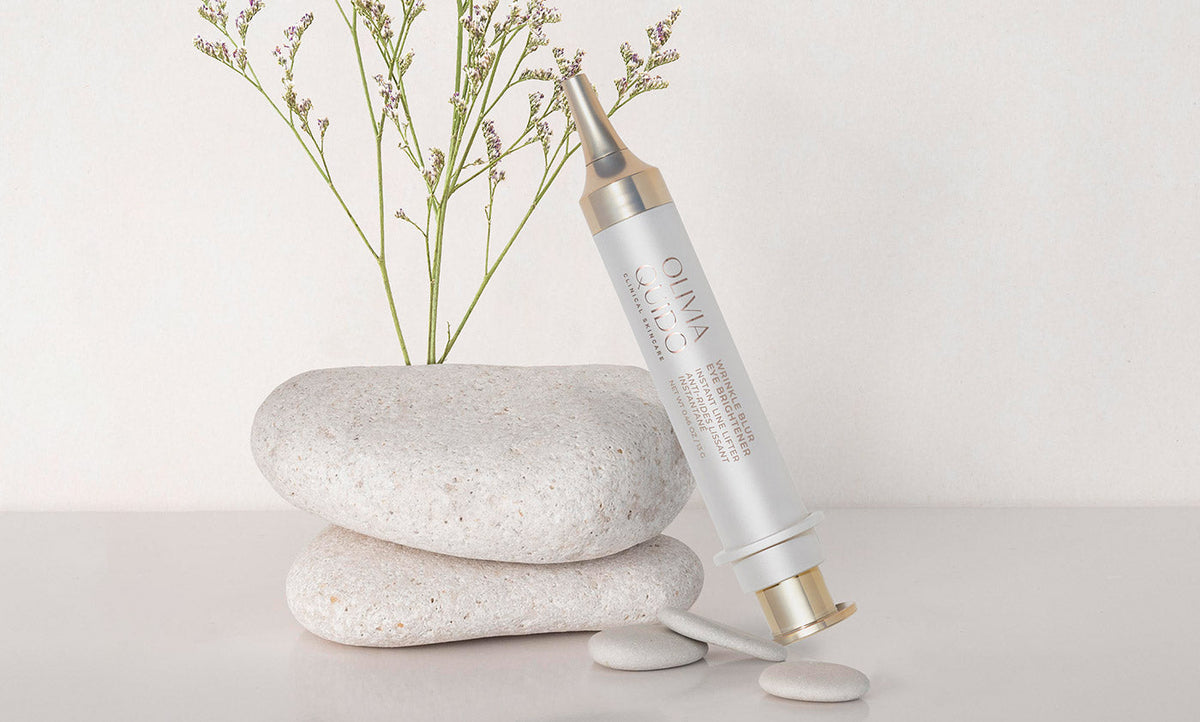 Olivia Quido Skincare Wrinkle Blur Eye Brightener  cream leaning on a stone in an environment. 